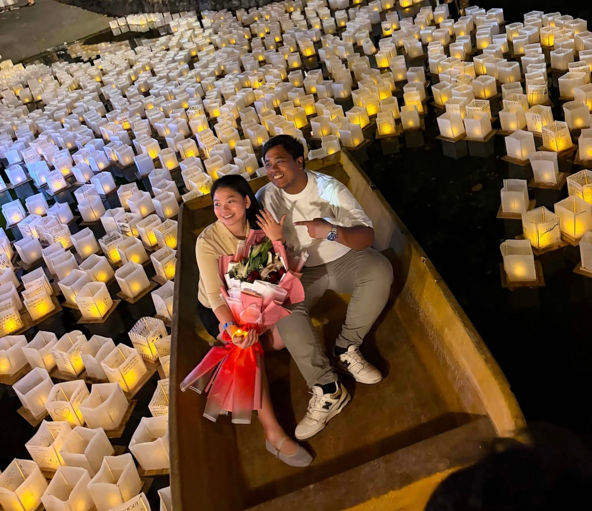 Couple celebrating an engagement on a boat surrounded by thousands of water lanterns